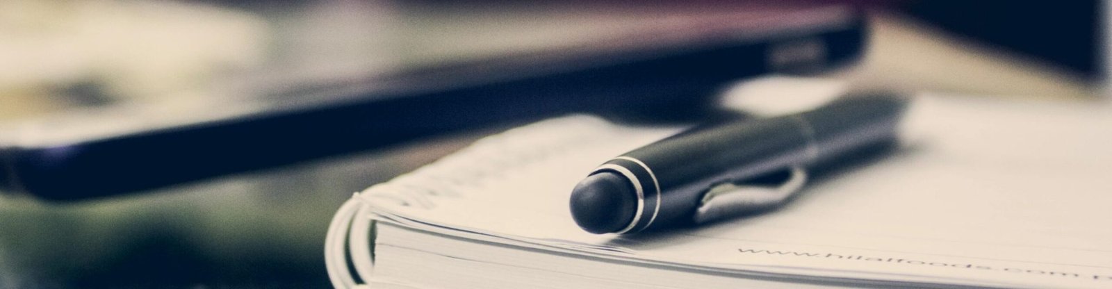 Close-up of an elegant pen resting on an open notebook in a stylish office environment.
