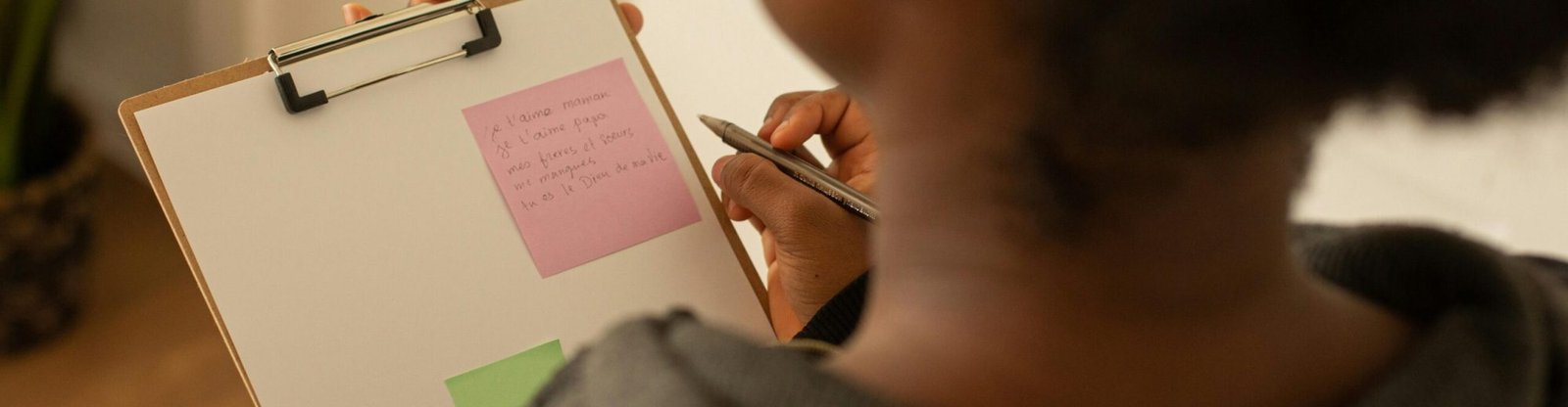 A woman writes notes on a clipboard with colorful sticky notes indoors.
