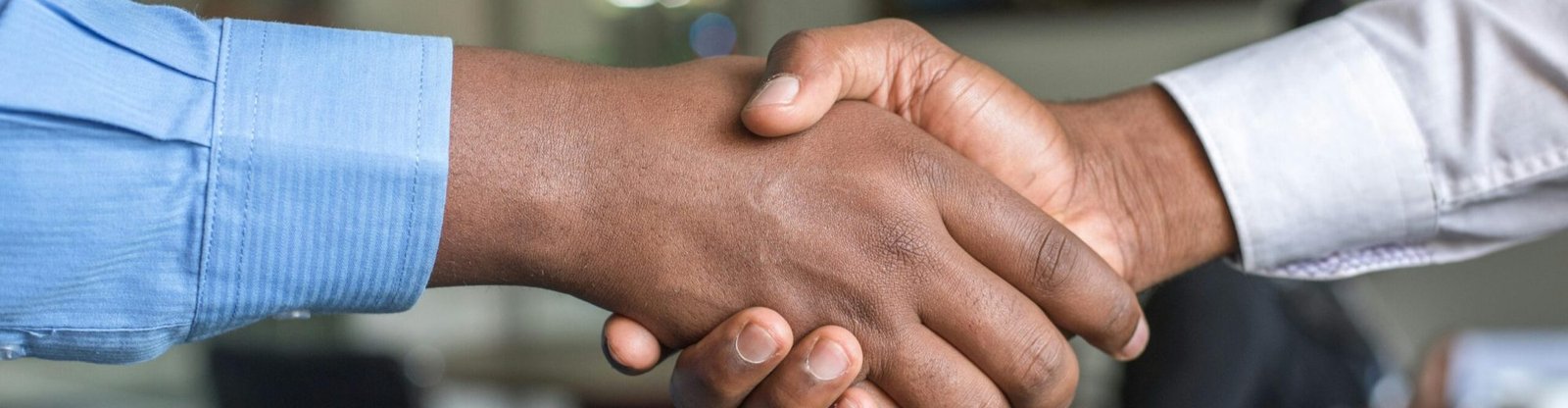 Close-up of two men's handshake symbolizing agreement in an office.